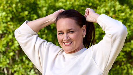 Woman smiling and fixing hair tie.