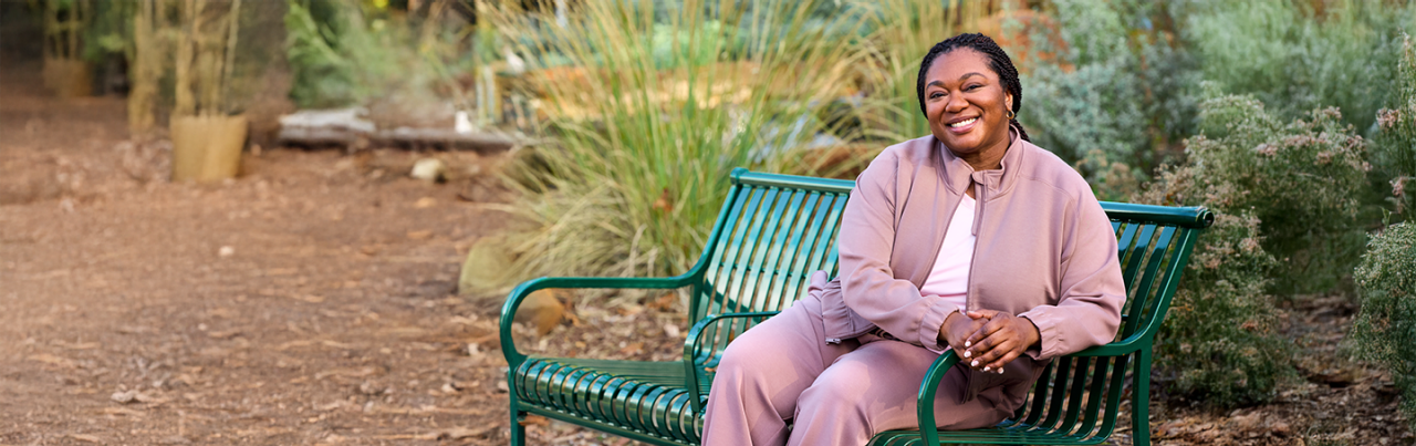 Woman seating and smiling on park bench.